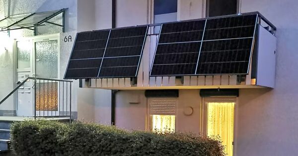 Solar panels mounted on a balcony railing of an apartment building at dusk