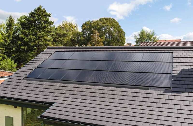 An in-roof solar panel array flush-mounted in a dark slate tiled roof of a house