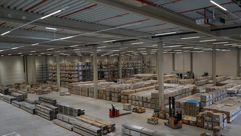 A large warehouse interior of Schletter's logistics centre with pallets of boxed solar mounting stock, racking and forklifts