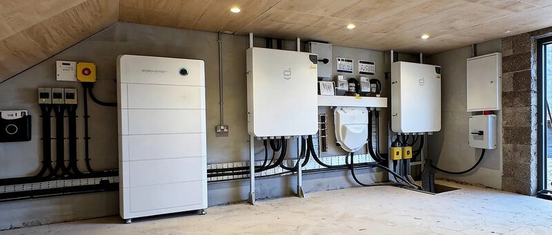 A Sigenergy SigenStor home battery and inverter installation mounted on a concrete wall in a utility room