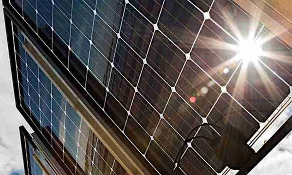 Close-up of bifacial solar panels mounted on a frame with bright sunlight glinting off the glass