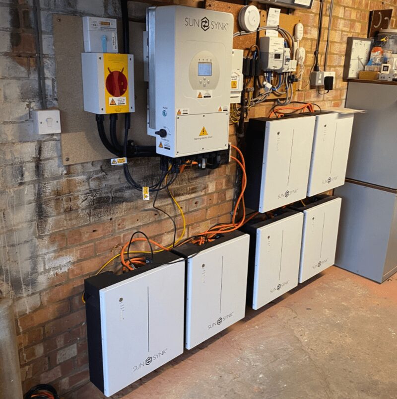 SunSynk solar battery storage units and an inverter installed on a garage wall with cabling and an emergency switch