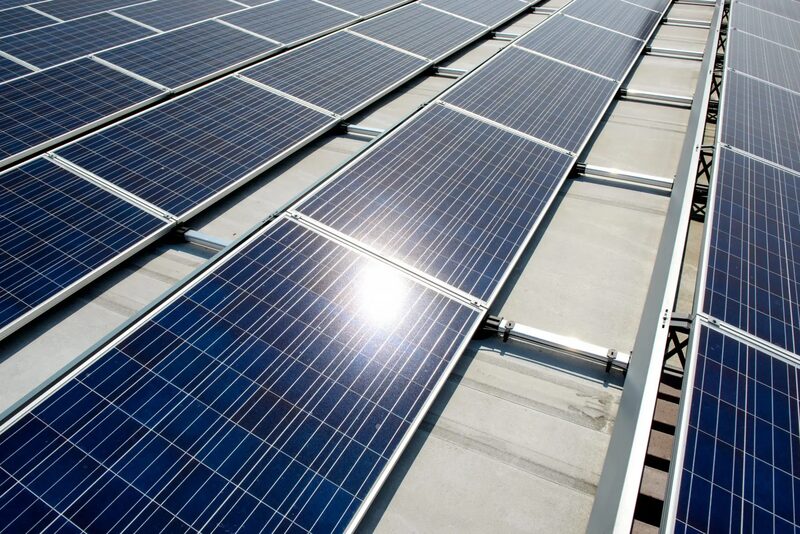 Rows of solar panels mounted on a flat roof with metal mounting rails