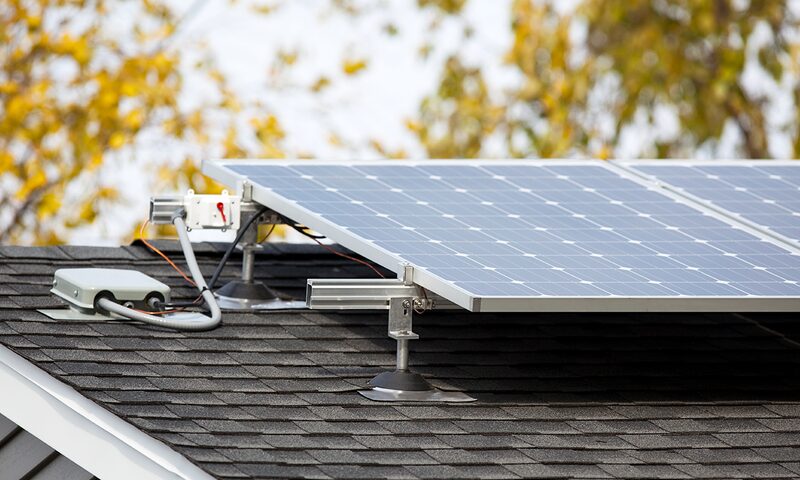 Solar panels mounted on a shingled roof with visible mounting brackets and wiring