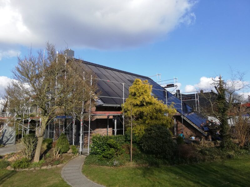 A house with its roof fully covered in solar panels, surrounded by scaffolding during installation