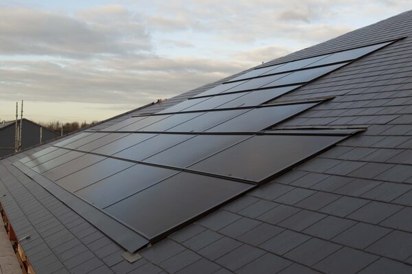In-roof solar PV panels flush-mounted among dark roof tiles on a large sloping roof