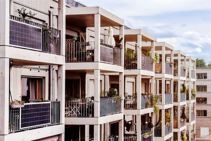 Apartment building balconies fitted with plug-in solar panels, plants and outdoor furniture