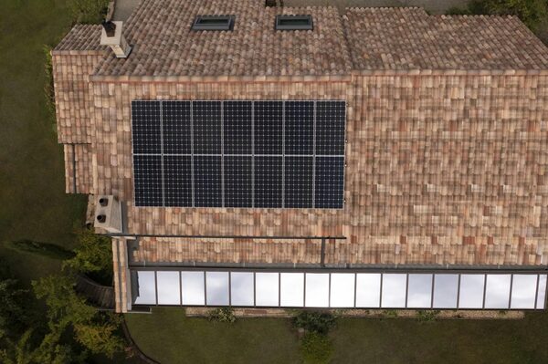 Aerial view of a tiled house roof with a large array of solar panels installed on it