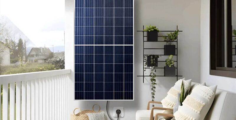 A balcony solar panel kit mounted on a balcony wall next to a sofa and plant shelf