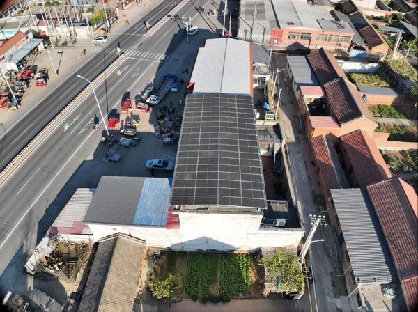Aerial view of a rooftop solar panel array on a building beside a road in a village