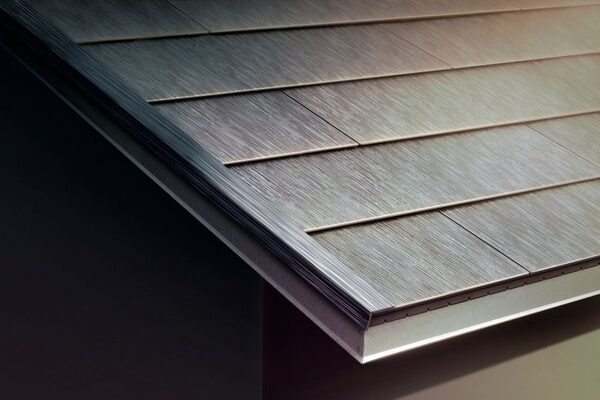 A close-up of a dark solar roof tile installation on the edge of a pitched roof