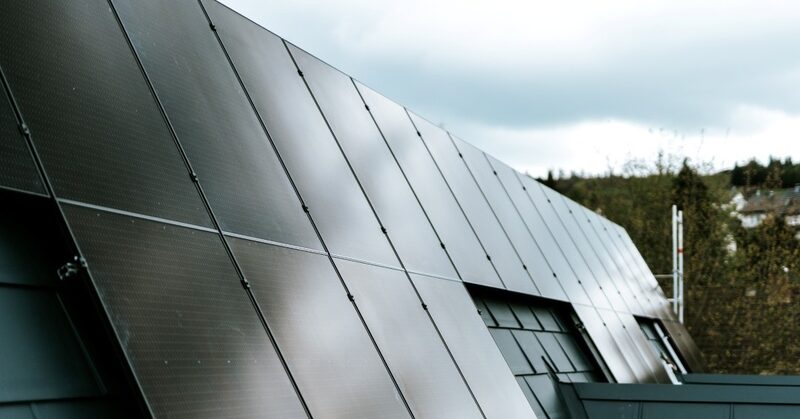 A close-up view of dark solar panels installed on a sloped roof under an overcast sky