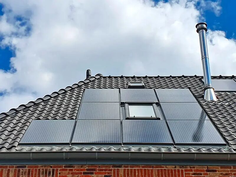 Roof-integrated solar PV panels fitted around a VELUX roof window on a tiled roof with a stainless flue