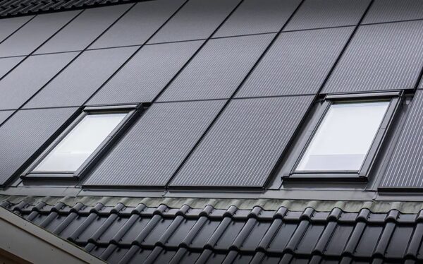 A roof with dark solar panels installed around two roof windows above tiled roofing
