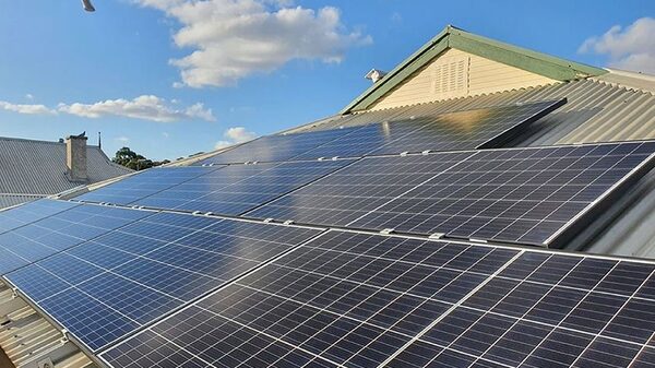 Solar panels installed on a corrugated metal roof of a house under a blue sky