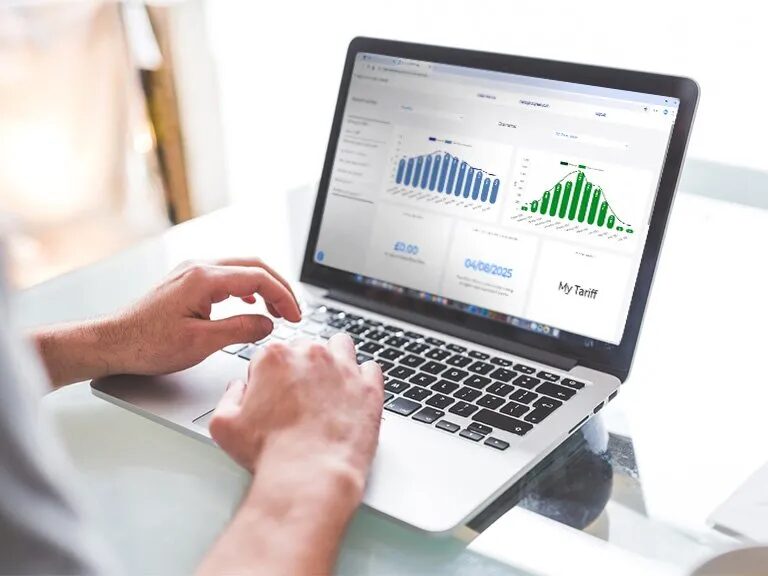 A person typing on a laptop displaying an energy tariff dashboard with bar charts and a 'My Tariff' panel