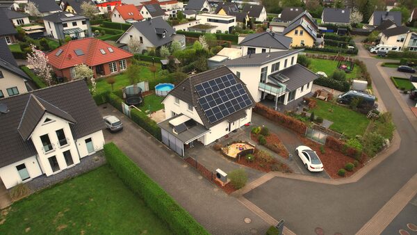 Aerial view of a suburban neighbourhood with a house roof covered in solar panels