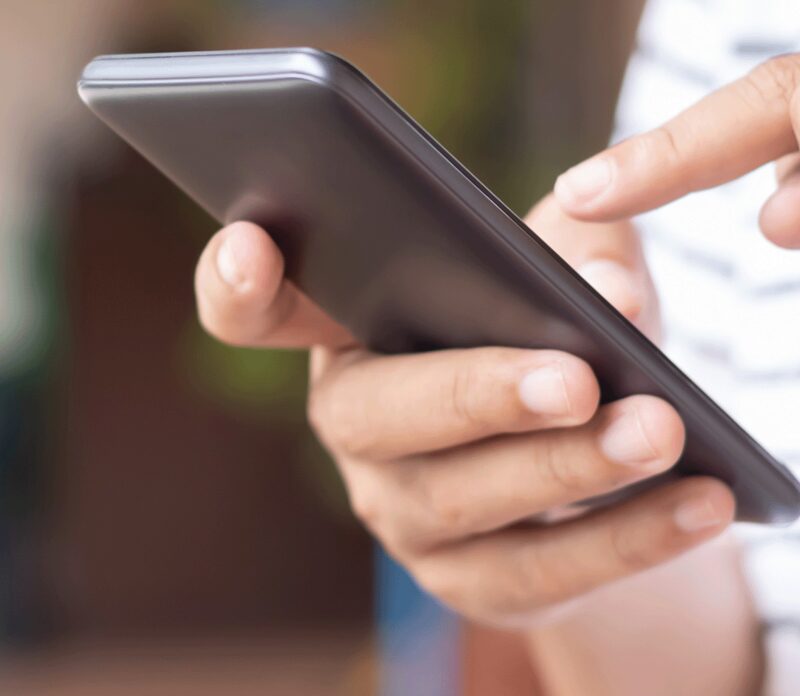 A person's hands holding and tapping on a smartphone