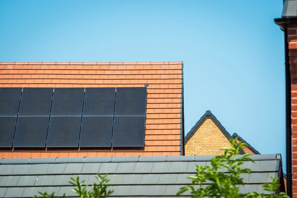 Solar panels installed on a red-tiled house roof against a blue sky