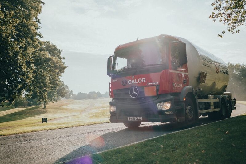 A red Calor LPG tanker lorry driving along a country road