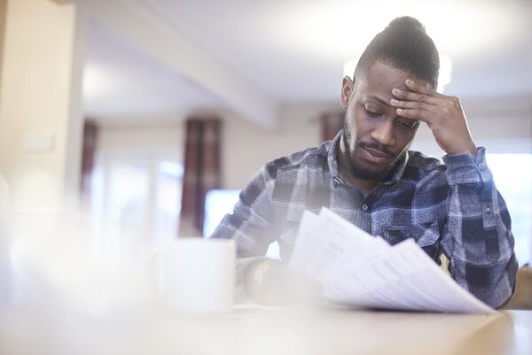 A worried man sitting at a table at home reading a paper energy bill
