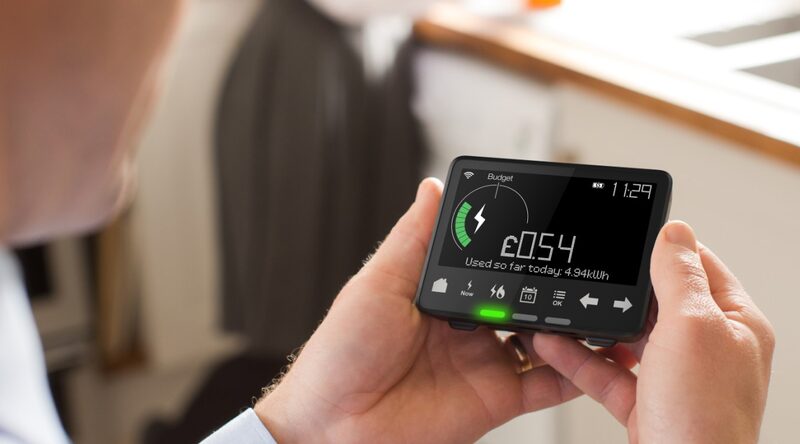 A man holding a smart meter in-home display showing energy use of £0.54 and 4.94 kWh today