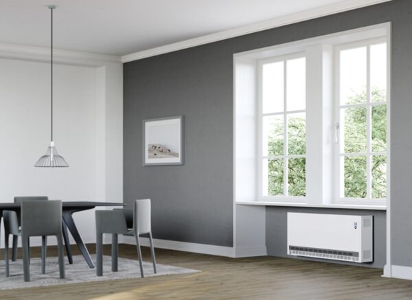 A white Stiebel Eltron storage heater installed on the wall below a window in a grey dining room