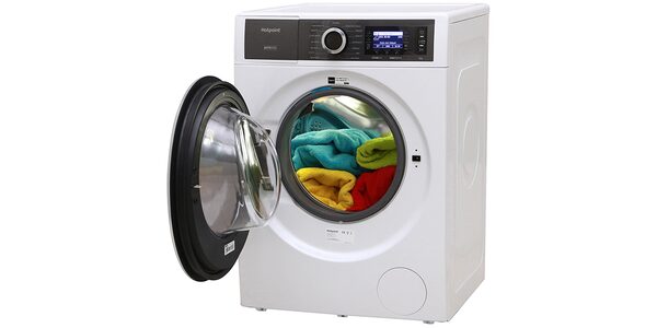 A white Hotpoint washing machine with its door open, loaded with colourful towels