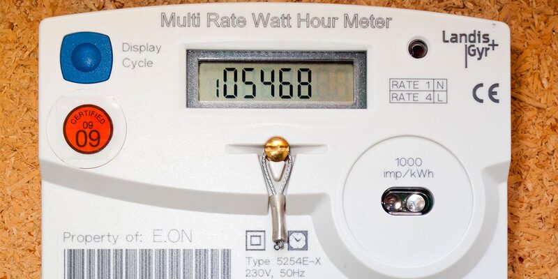 A close-up of a Landis+Gyr multi-rate electricity meter with digital display, mounted on a wooden surface