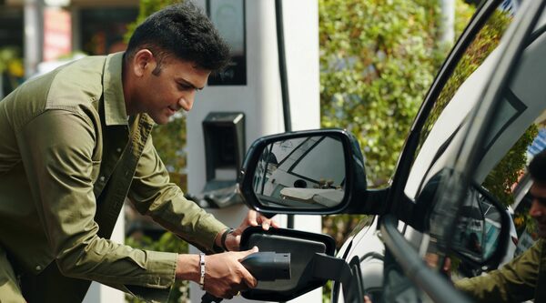 A man plugging a charging cable into an electric car at a public charge point