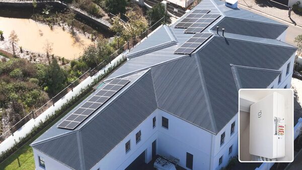 Aerial view of a house roof with solar panels, with an inset photo of a white wall-mounted energy gateway unit