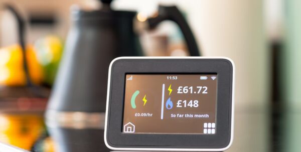 A smart meter in-home display on a kitchen counter showing electricity and gas costs so far this month
